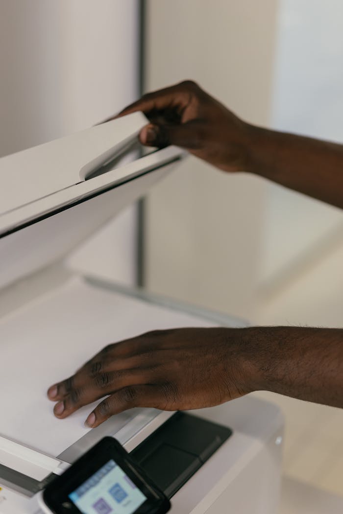 Hands adjusting document on a scanner in an office environment.